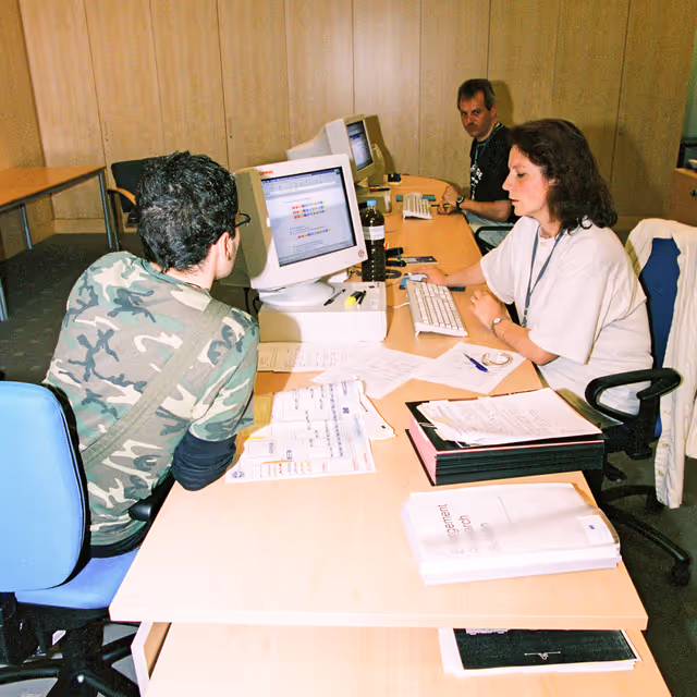 Foto 12: People consulting documents at the Infopoint