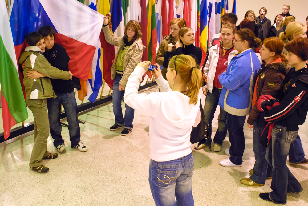 Teenagers taking a picture in front of various flags of country members of the European Union in 2007
