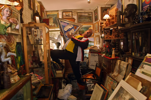 Photo 7: A hungarian saler sings among his art paints in the Budapest oldest junk and antiques market Ecseri