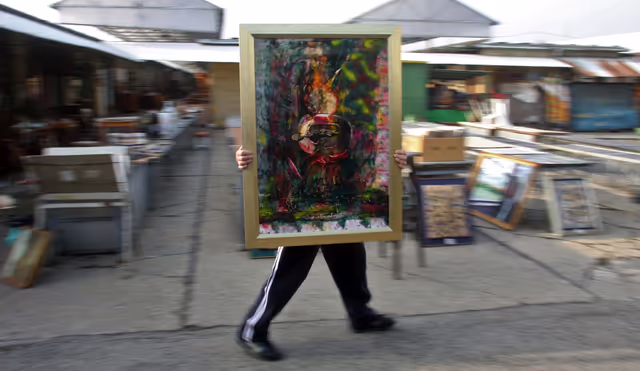 Photo 4: A hungarian saler brings a paint in the Budapest oldest junk and antiques market Ecseri